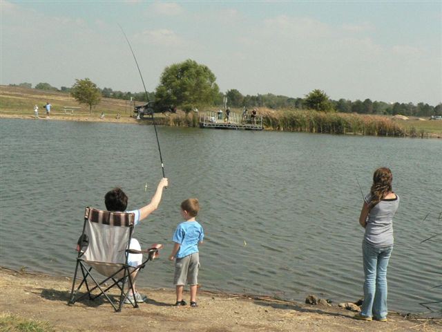 A family of four fishing together on a serene lake
